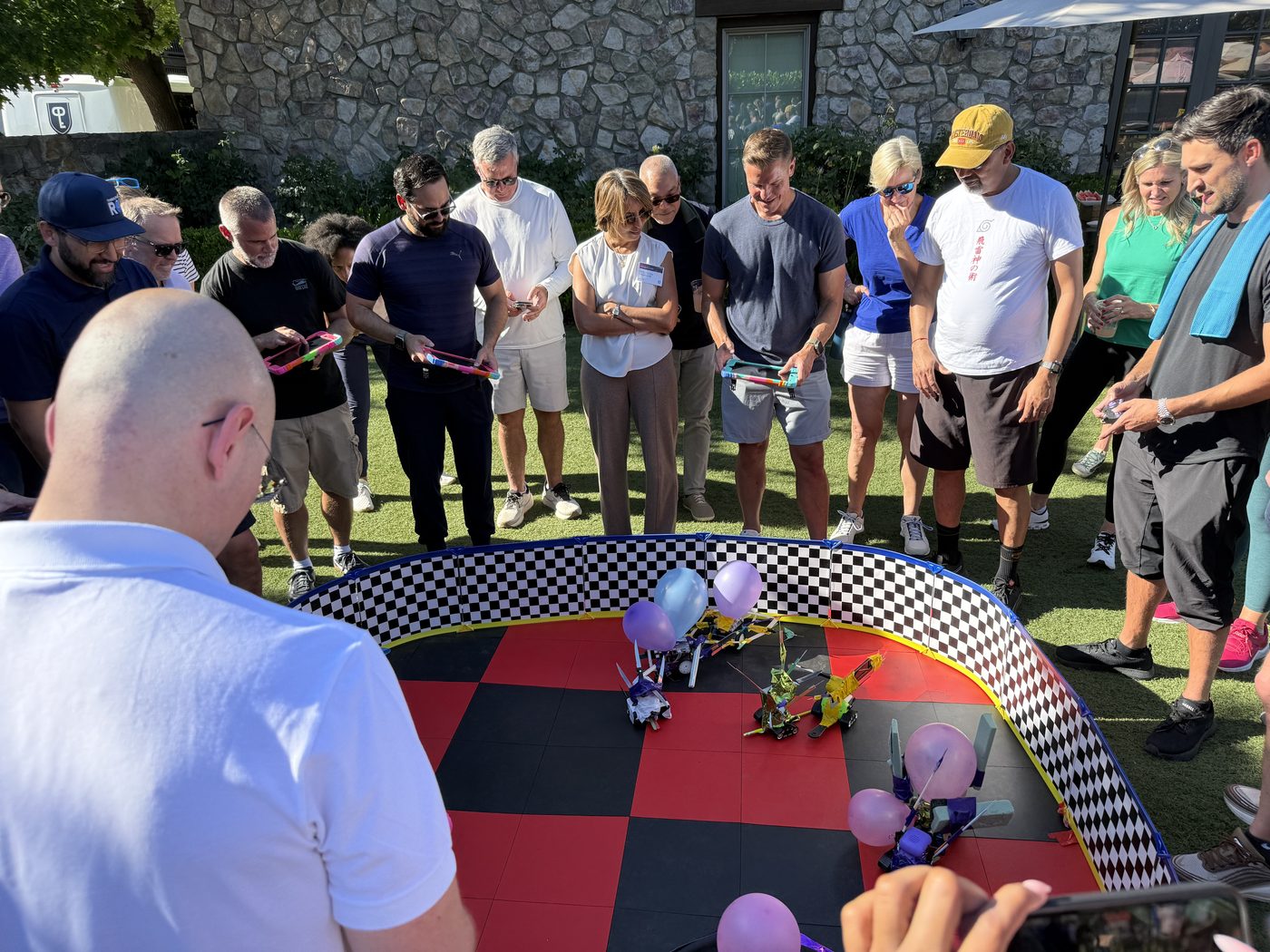 An enthusiastic crowd gathers around the real Robot Rally arena outdoors